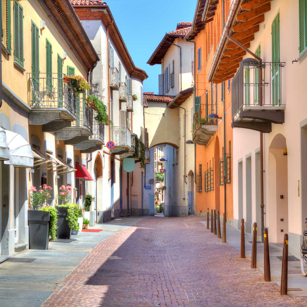 Narrow stone paved street among colorful houses in town of Alba in Piedmont, Northern Italy.
